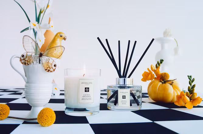 A fresh and modern arrangement of Jo Malone London candles and diffusers, styled with yellow florals and sculptural vases.